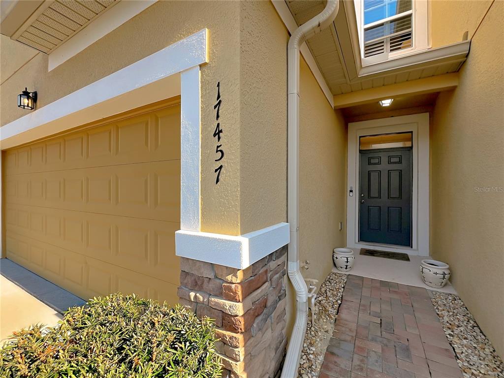 The exterior of a house shows a garage, a front door, and stone accents — 17457 CHATEAU PINE WAY, CLERMONT, FL