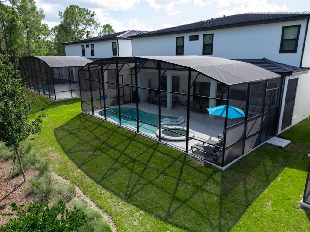 An aerial view of two houses with screened-in pools and patios in a grassy backyard — 1443 BUTTERFLY MILKWEED COURT, DAVENPORT, FL