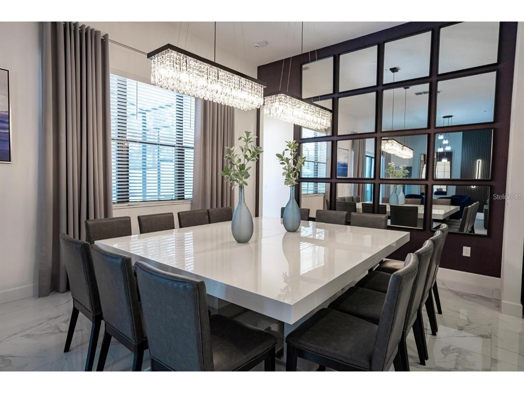 A dining room features a large square white table, gray upholstered chairs, and mirrored walls — 1443 BUTTERFLY MILKWEED COURT, DAVENPORT, FL