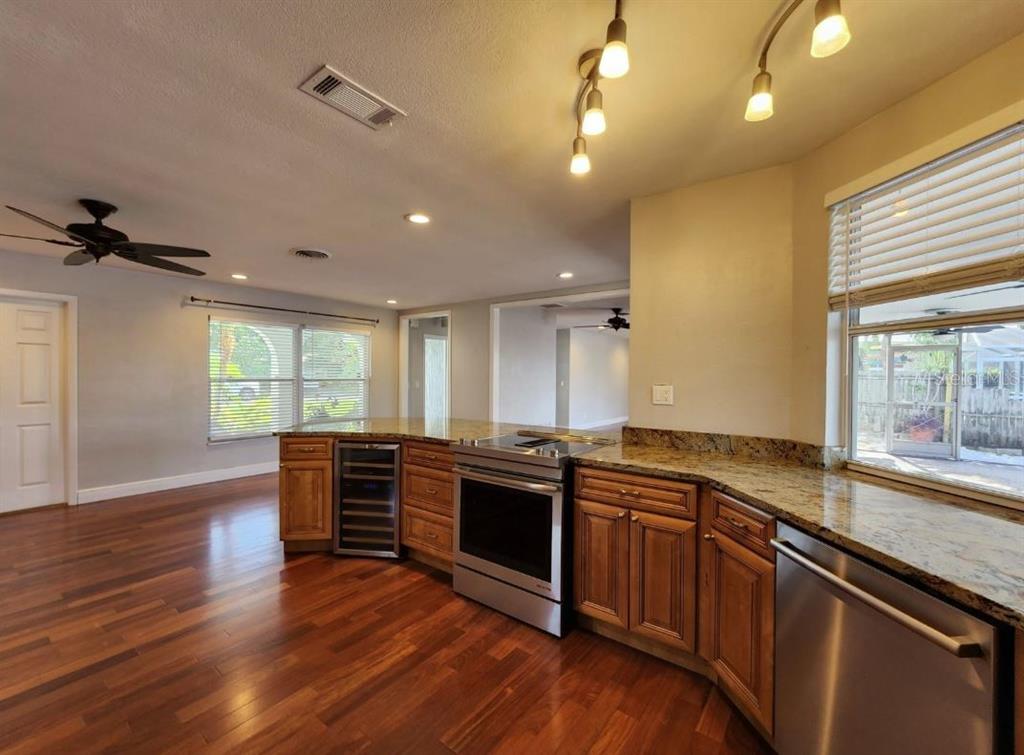 A kitchen with wood cabinets, granite countertops, stainless steel appliances, and hardwood floors — 128 98TH AVENUE N, ST PETERSBURG, FL