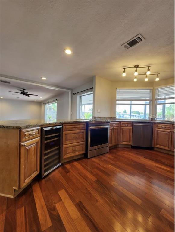 A kitchen with wood cabinets, stainless steel appliances, and hardwood floors under recessed lighting — 128 98TH AVENUE N, ST PETERSBURG, FL