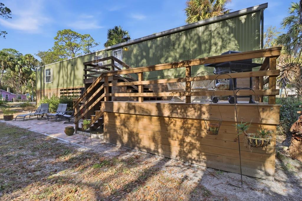 A green mobile home features a large wooden deck with stairs and a brick patio — 24 62ND STREET, YANKEETOWN, FL
