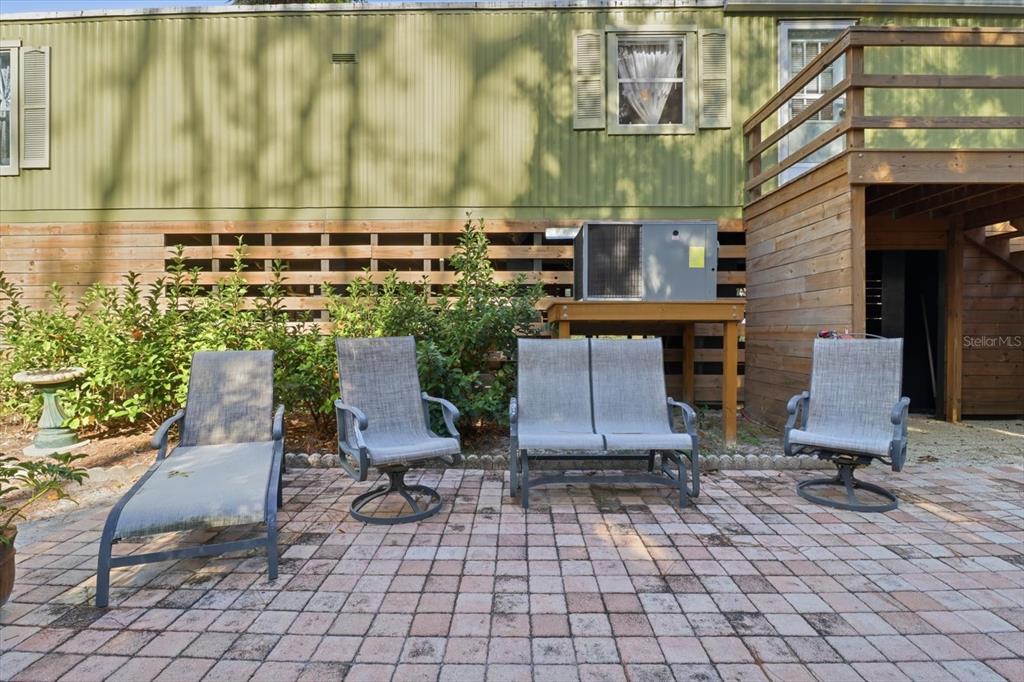 A patio with outdoor furniture sits in front of a green house with a wooden deck — 24 62ND STREET, YANKEETOWN, FL
