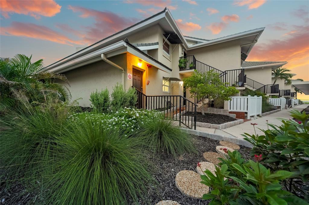 A two-story stucco building with exterior staircases and landscaping at sunset — 4660 OCEAN BOULEVARD UNIT F1, SARASOTA, FL