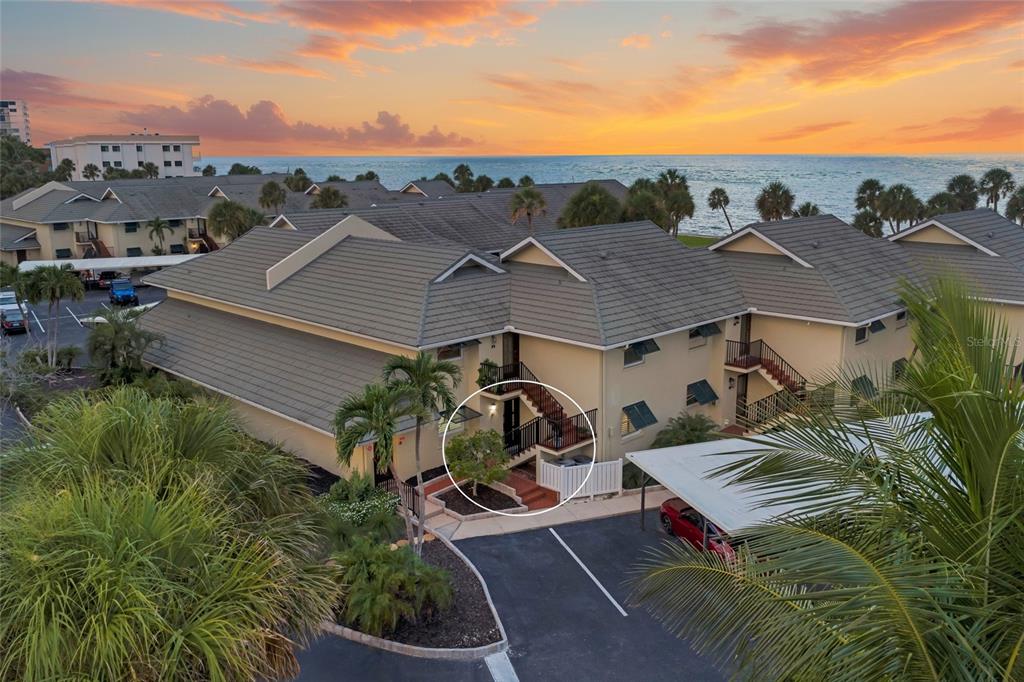 An exterior view of a multi-story apartment building with a circled staircase and parking area — 4660 OCEAN BOULEVARD UNIT F1, SARASOTA, FL