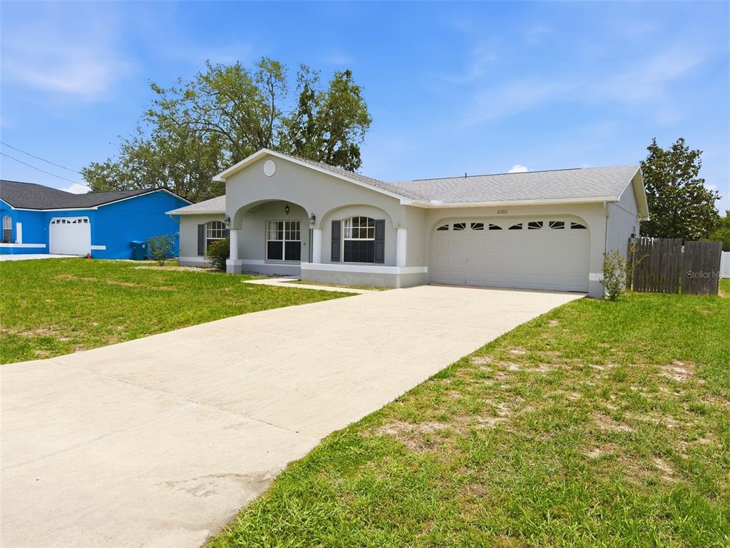 A single-story house with a concrete driveway, arched entryway, and a two-car garage — 2202 GODFREY AVENUE, SPRING HILL, FL