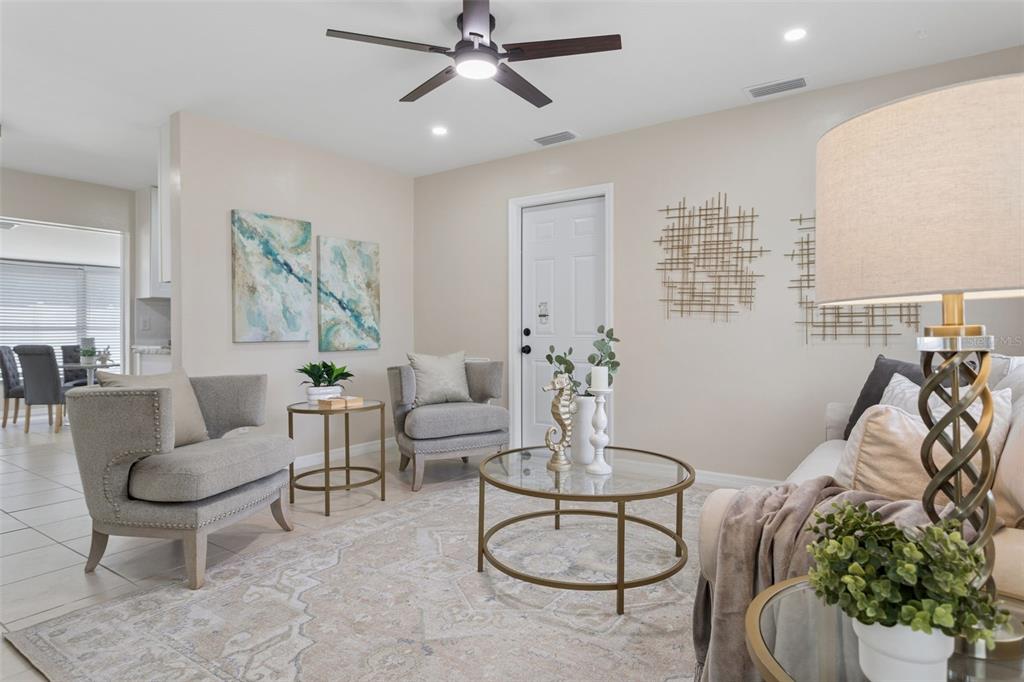 A living room features two gray armchairs, a glass coffee table, and a ceiling fan — 10926 TEMPLE AVENUE, SEMINOLE, FL