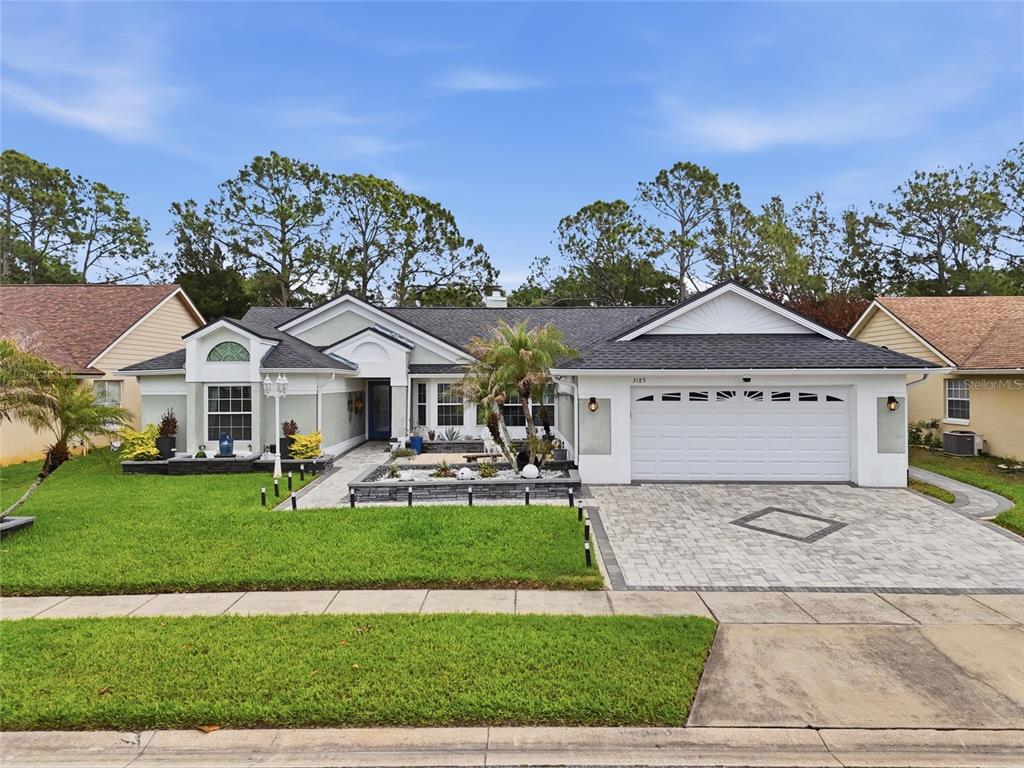 A single-story house with a white garage, stone-accented landscaping, and a paved driveway — 3185 TIMUCUA CIRCLE, ORLANDO, FL