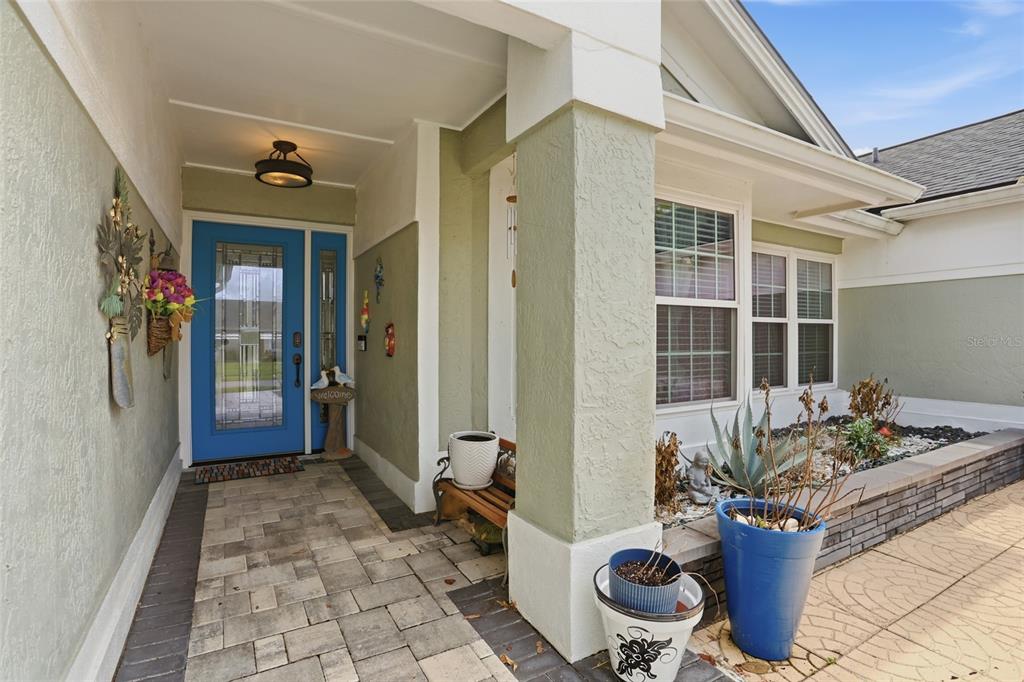A covered entryway features a blue front door, stone pavers, and a small wooden bench — 3185 TIMUCUA CIRCLE, ORLANDO, FL