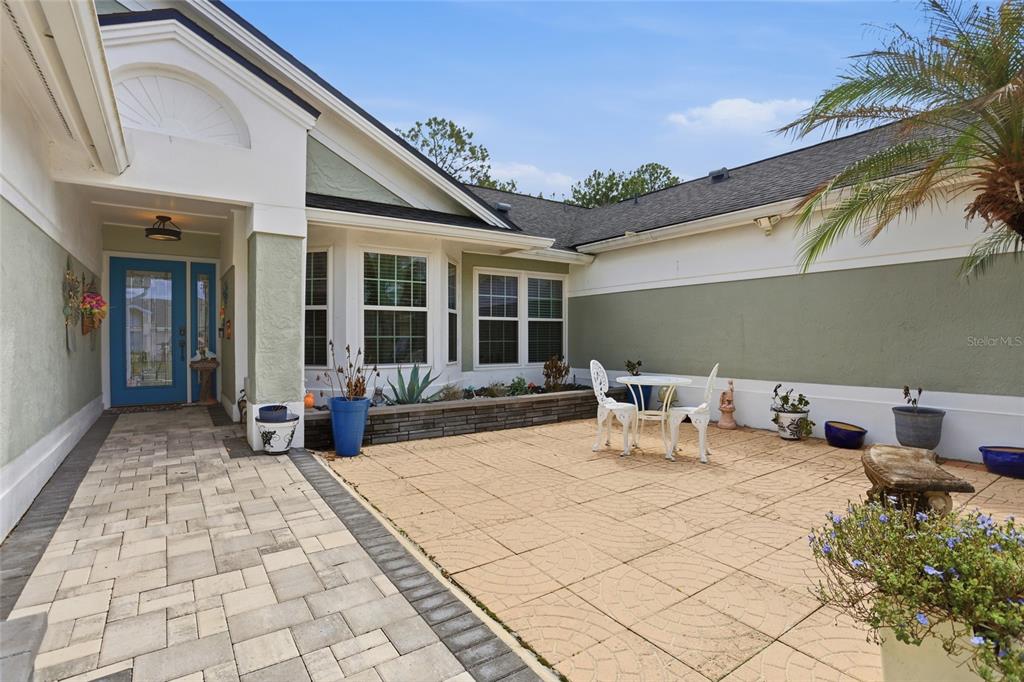 A paved courtyard features a small bistro set, potted plants, and a blue front door — 3185 TIMUCUA CIRCLE, ORLANDO, FL