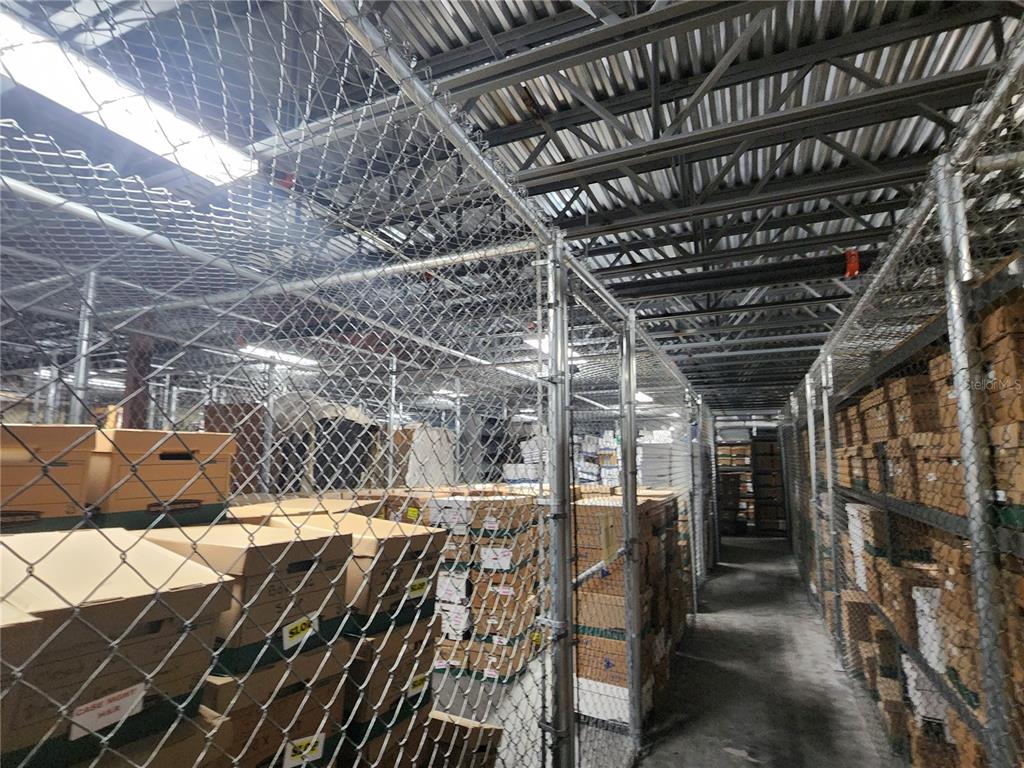 A storage area features metal shelving units enclosed by chain-link fencing and cardboard boxes — 711 N 3RD ST, LEESBURG, FL