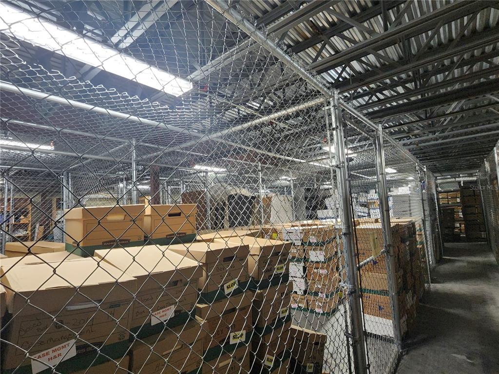 A storage area features metal chain-link fencing enclosing stacks of cardboard boxes on shelves — 711 N 3RD ST, LEESBURG, FL