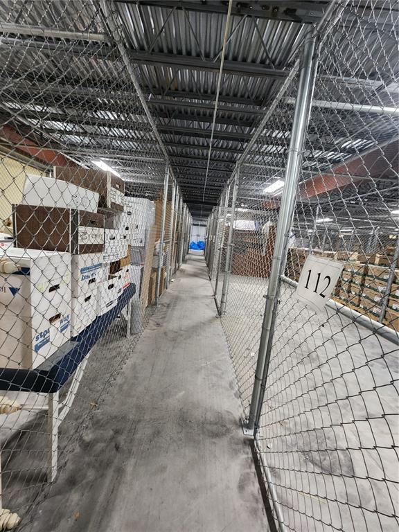 A narrow storage unit hallway features chain-link fencing and stacked cardboard boxes on shelves — 711 N 3RD ST, LEESBURG, FL