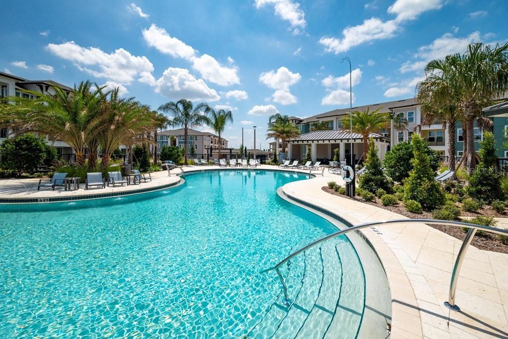 A resort-style swimming pool with lounge chairs, palm trees, and surrounding apartment buildings — 15000 STRATUS LOOP UNIT C1, WINTER GARDEN, FL