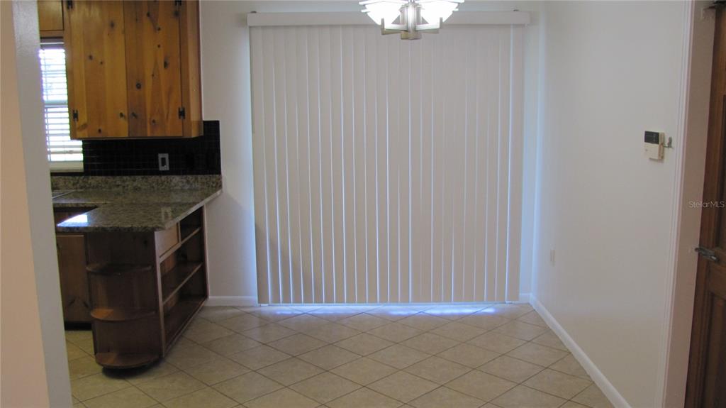 A dining area features tile flooring, a sliding glass door, and a kitchen peninsula — 1803 W LOUISIANA AVENUE, TAMPA, FL