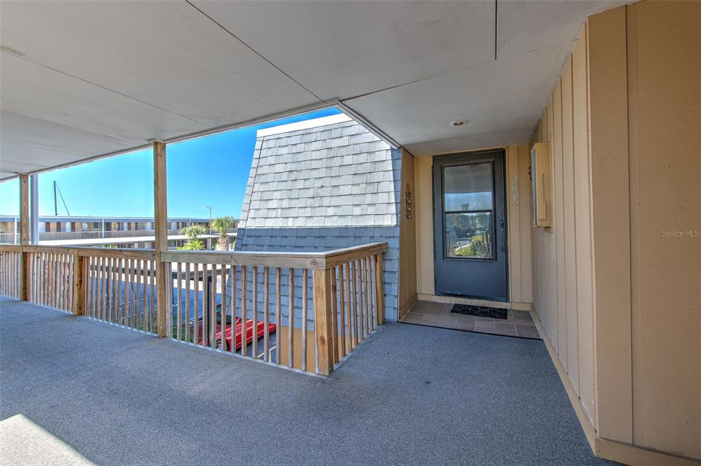 A covered outdoor walkway leads to a front door with a wooden railing — 1008 APOLLO BEACH BOULEVARD UNIT 201, APOLLO BEACH, FL
