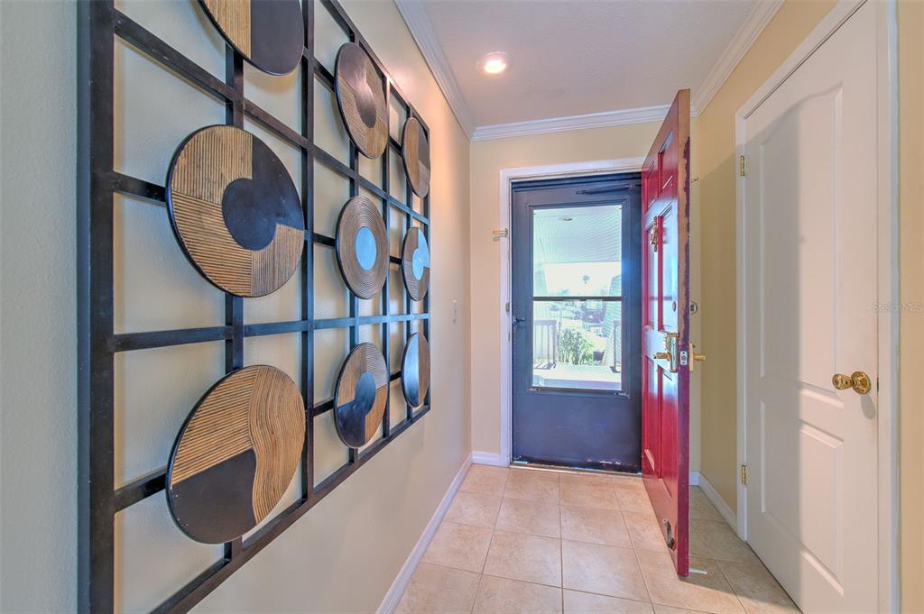 An entryway features a red front door, tiled flooring, and a large geometric wall decoration — 1008 APOLLO BEACH BOULEVARD UNIT 201, APOLLO BEACH, FL