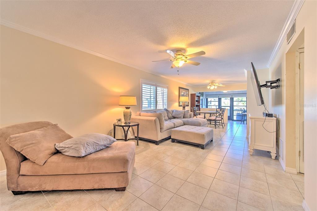 A living room with tile flooring, a beige sectional, a chaise lounge, and a ceiling fan — 1008 APOLLO BEACH BOULEVARD UNIT 201, APOLLO BEACH, FL