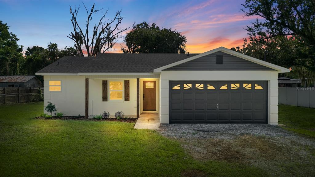 A single-story house with a white exterior, dark garage door, and a wooden front door — 414 S WIGGINS ROAD, PLANT CITY, FL