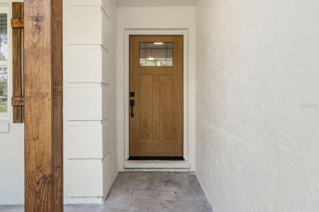 A wooden front door with a glass pane is set within a white stucco entryway — 414 S WIGGINS ROAD, PLANT CITY, FL