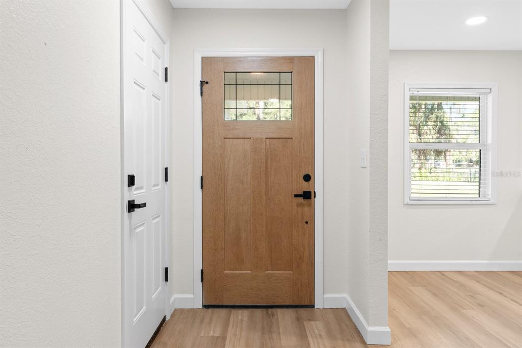 An entryway features a wood-toned front door with a glass panel and light wood flooring — 414 S WIGGINS ROAD, PLANT CITY, FL