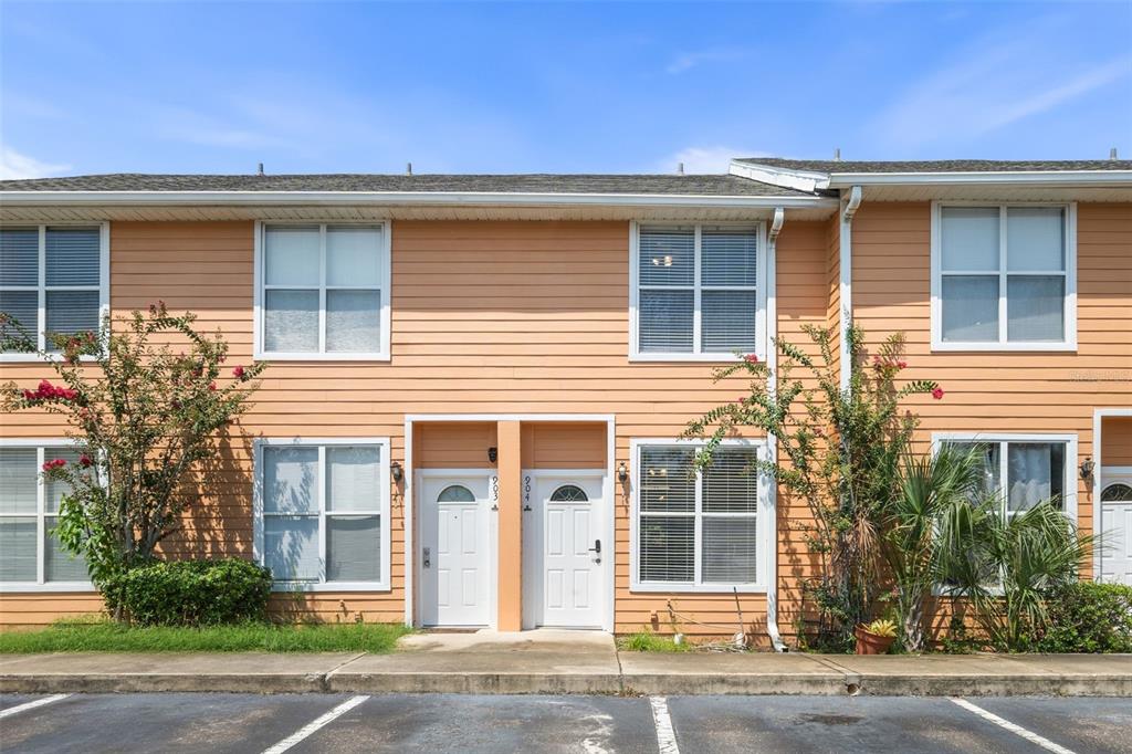 A two-story townhouse exterior with peach siding, white trim, and two adjacent front doors — 3970 SW 20TH AVENUE UNIT 904, GAINESVILLE, FL