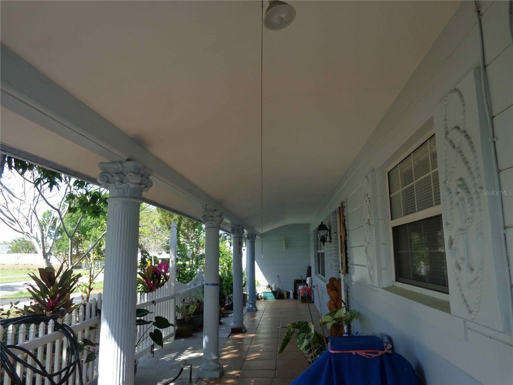 A covered porch features white columns, tile flooring, and a white picket fence — 6165 26TH AVENUE N, ST PETERSBURG, FL
