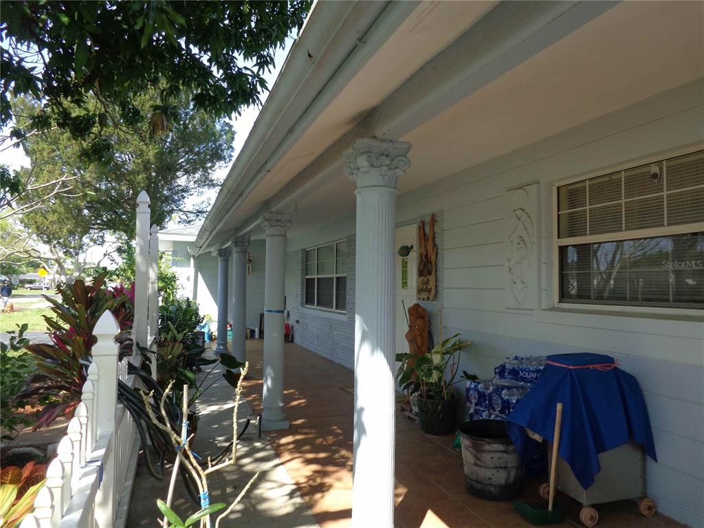 A covered front porch features white columns, a tiled floor, and a white picket fence — 6165 26TH AVENUE N, ST PETERSBURG, FL