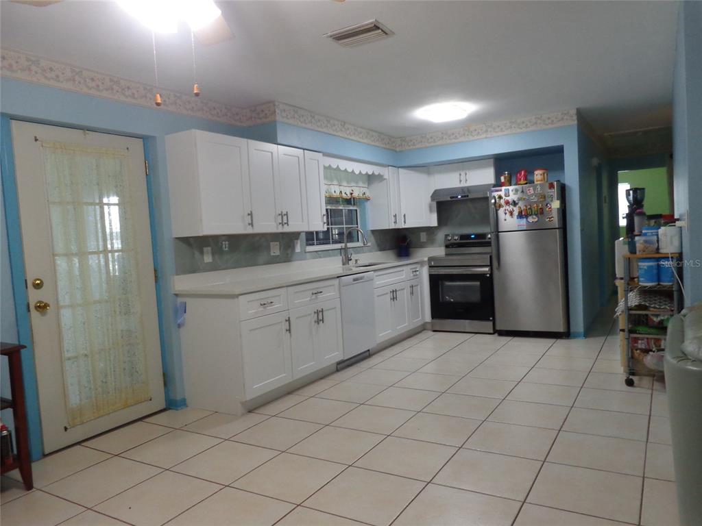 A kitchen features white cabinets, stainless steel appliances, and light-colored tile flooring — 6165 26TH AVENUE N, ST PETERSBURG, FL