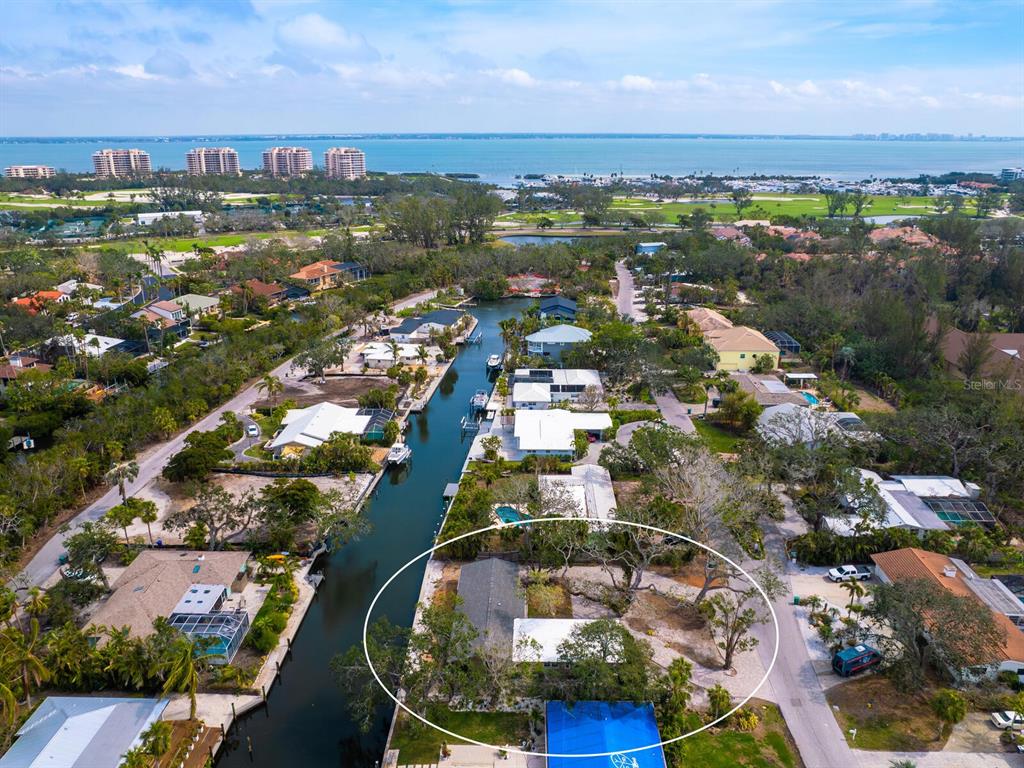 An aerial view shows a waterfront house with a large yard along a canal — 615 BUTTONWOOD DRIVE, LONGBOAT KEY, FL