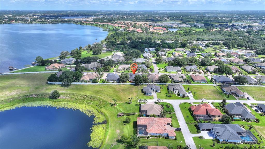 An aerial view shows a residential neighborhood with houses, a lake, and a pond — 9469 WATERFORD OAKS DRIVE, WINTER HAVEN, FL