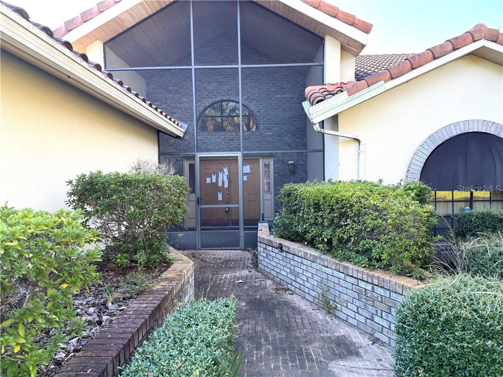 A brick-walled entryway is enclosed by a screen and features a paved walkway — 6135 W Pine Ridge BOULEVARD, BEVERLY HILLS, FL
