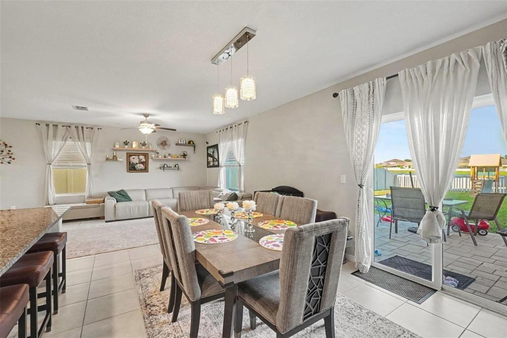 A dining area with a table and chairs sits adjacent to a living room and patio — 3166 OYSTER COVE STREET, WIMAUMA, FL