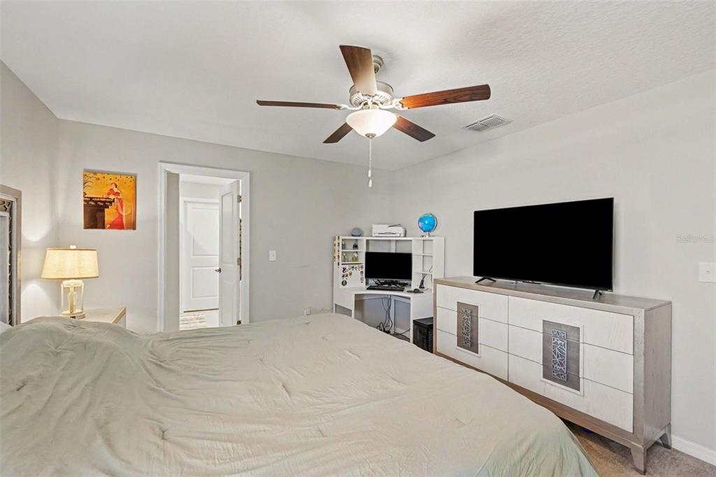 A bedroom features a bed, a dresser with a television, and a corner desk unit — 3166 OYSTER COVE STREET, WIMAUMA, FL