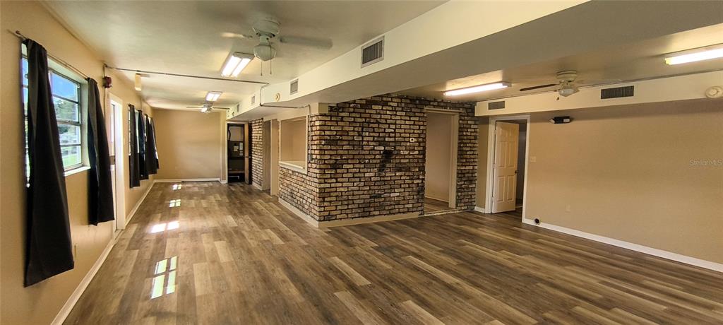 A large room features wood-look flooring, a brick accent wall, and multiple ceiling fans — 14610 KENNARD STREET, WALDO, FL