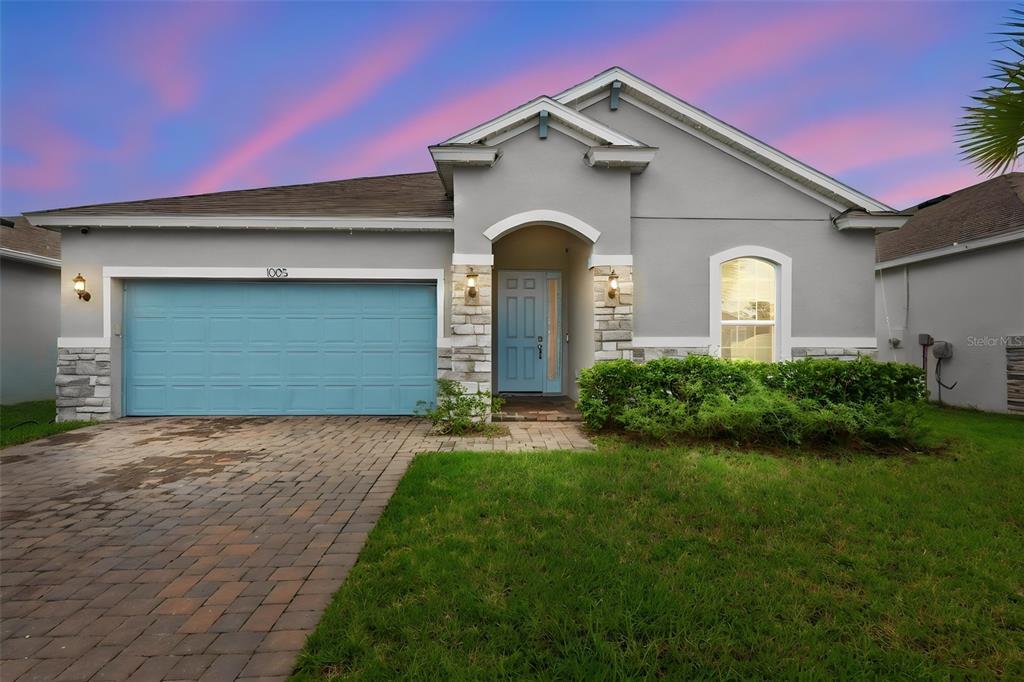 A single-story house with a light blue garage door, stone accents, and a paved driveway — 1005 CHELAN FALLS DRIVE, DELAND, FL
