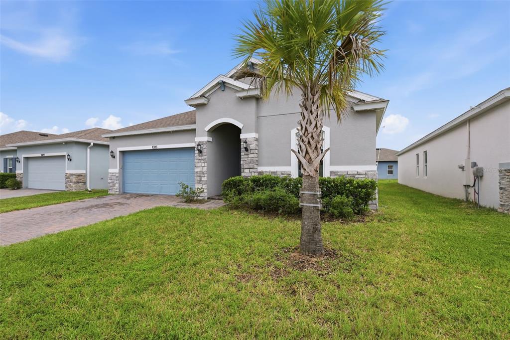 A single-story suburban house with a gray stucco exterior, stone accents, and a palm tree — 1005 CHELAN FALLS DRIVE, DELAND, FL