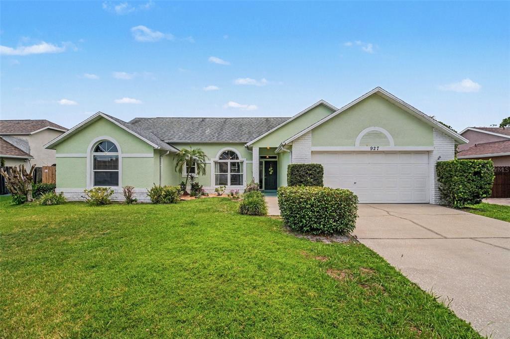 A single-story house with light green stucco siding, a two-car garage, and a front lawn — 927 JAMESTOWN DRIVE, ROCKLEDGE, FL
