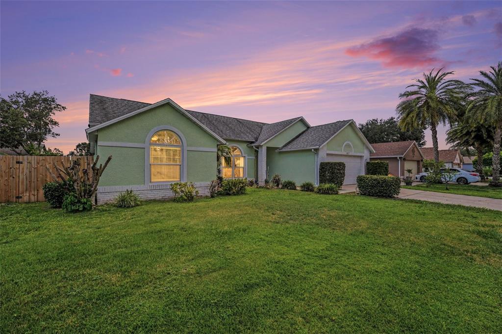 A light green single-story house with a front lawn and a two-car garage at sunset — 927 JAMESTOWN DRIVE, ROCKLEDGE, FL