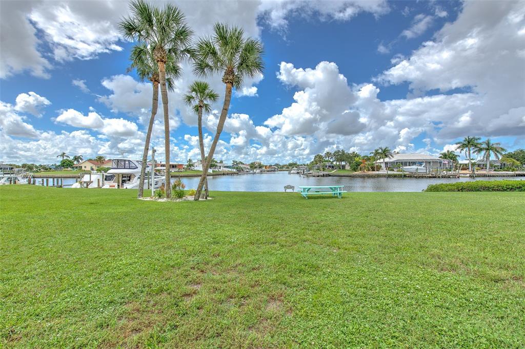 A grassy lawn with palm trees overlooks a canal with docked boats under a cloudy sky — 1028 APOLLO BEACH BOULEVARD UNIT 4, APOLLO BEACH, FL