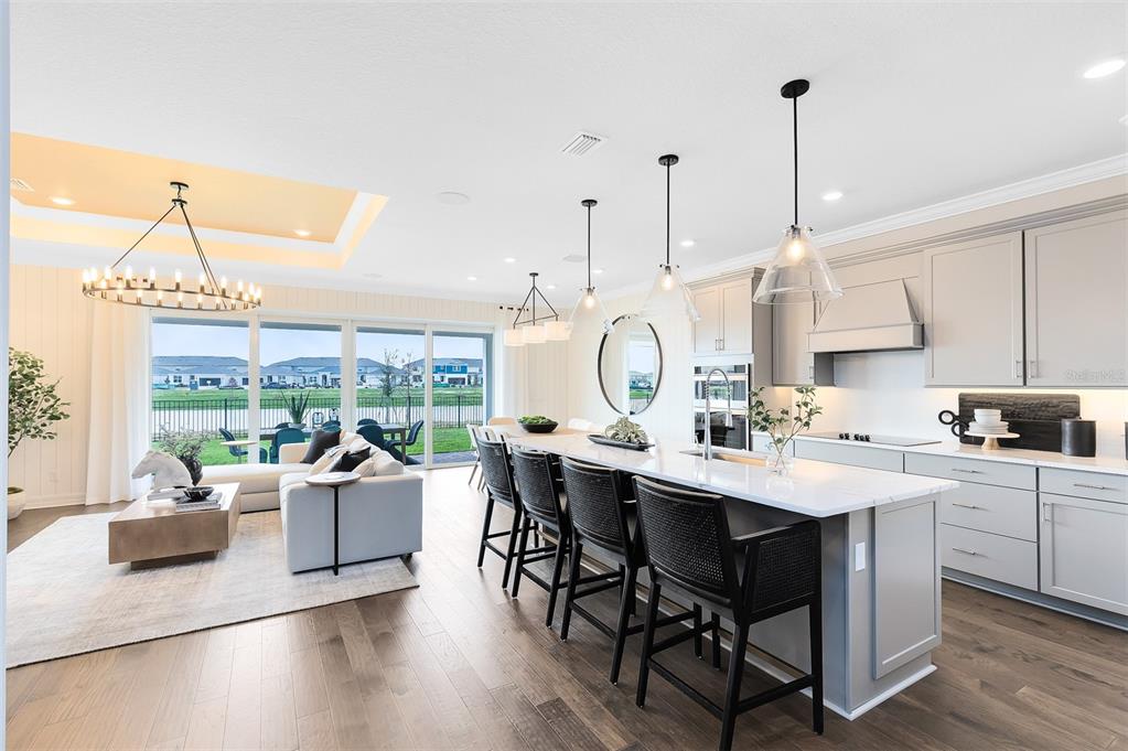 An open-concept kitchen and living area features a large island, pendant lighting, and sliding doors — 2204 BRANCHED OAK ROAD, ST CLOUD, FL