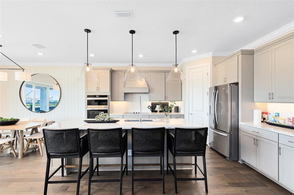 A modern kitchen features a large island with black bar stools and stainless steel appliances — 2204 BRANCHED OAK ROAD, ST CLOUD, FL