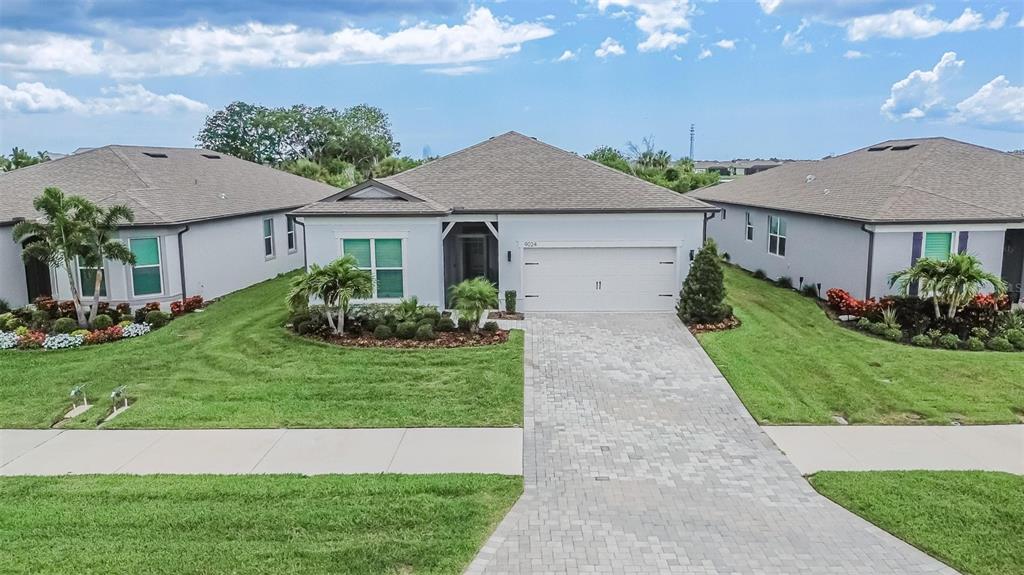 An aerial view of a single-story suburban house with a paved driveway and green lawn — 9024 BARRIER COAST TRAIL, PARRISH, FL