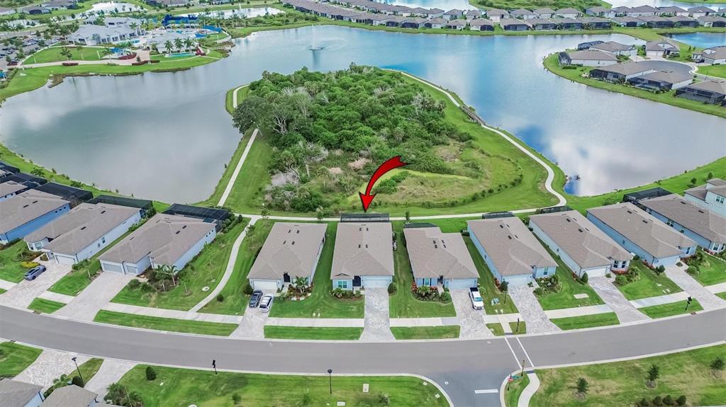 An aerial view shows a row of suburban houses situated along a lake and wooded area — 9024 BARRIER COAST TRAIL, PARRISH, FL