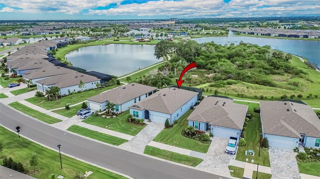 An aerial view shows a suburban house with a red arrow pointing to its roof — 9024 BARRIER COAST TRAIL, PARRISH, FL