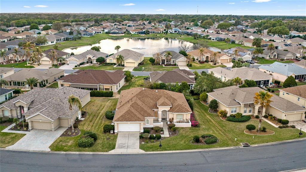 An aerial view shows suburban houses surrounding a central pond with a fountain — 9512 SE 124TH LOOP, SUMMERFIELD, FL