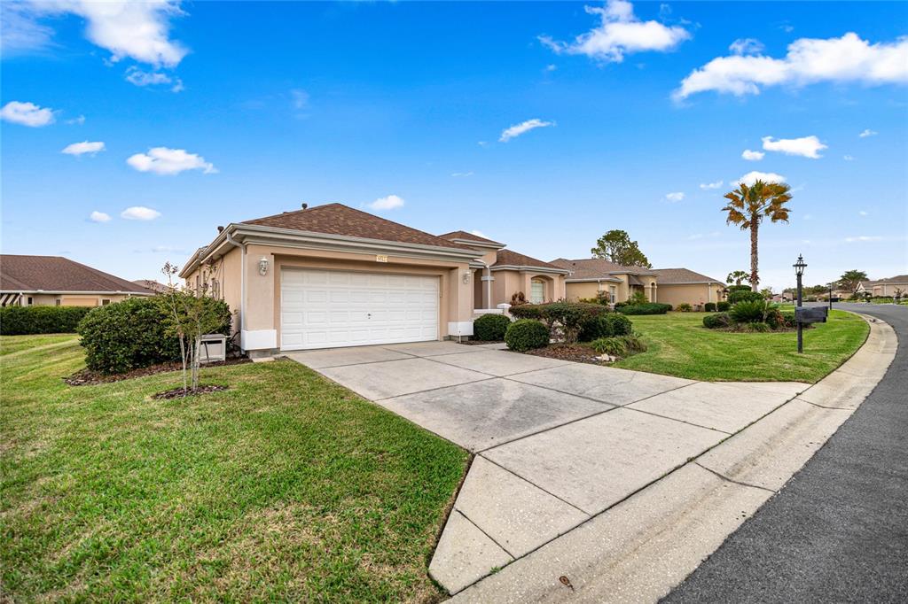 A single-story house with a two-car garage and a concrete driveway under a blue sky — 9512 SE 124TH LOOP, SUMMERFIELD, FL