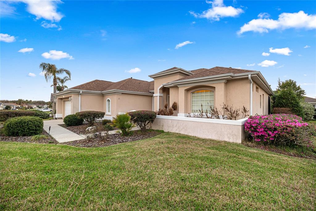 A single-story tan stucco house with a brown shingled roof and a front lawn — 9512 SE 124TH LOOP, SUMMERFIELD, FL