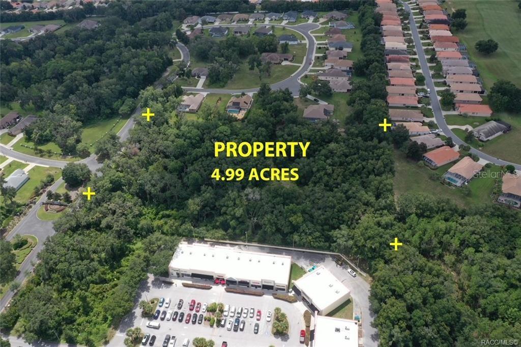An aerial view shows a wooded 4.99-acre plot of land surrounded by residential and commercial buildings — 2364 N HERITAGE OAKS PATH, HERNANDO, FL