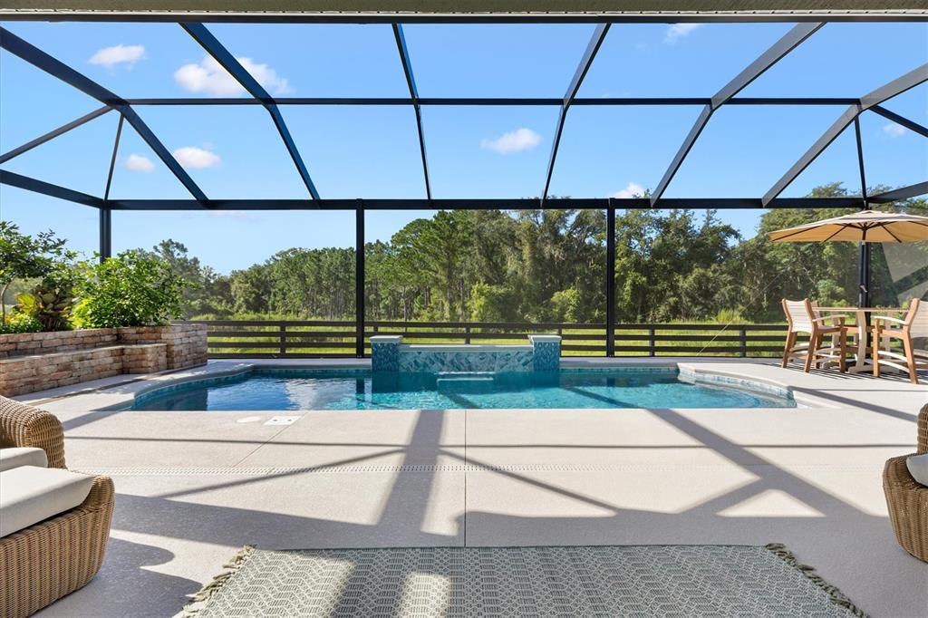 A screened-in patio features a swimming pool with a water feature and outdoor furniture — 504 BEDMINSTER WAY, THE VILLAGES, FL